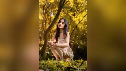 Elegant woman in a white lace dress posing in a sunlit, dreamy forest setting.