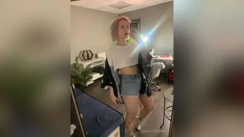 ScarlettGarrett poses in a white crop top and denim shorts, showing her midriff and tattoos in a mirror selfie.