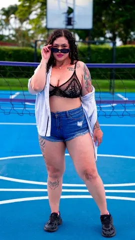 kayllaEvanss wearing a black lace bra and denim shorts with an open white shirt and sunglasses, posing on a blue basketball court.