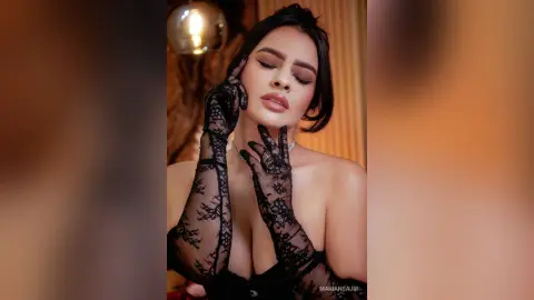 Glamorous woman in black lace gloves and elegant jewelry posing with a moody, sophisticated expression.