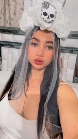 Woman in white bridal veil and skull headpiece posing with a romantic, ethereal mood.