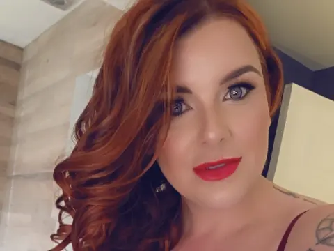 SavanahRosexxx — SavanahRosexxx is a redhead with bright red lipstick posing for a close-up selfie indoors.