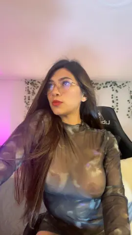 MadelineBrooks wears a sheer, tight grey long-sleeve top that shows her nipples and breasts while she sits in a gaming chair.