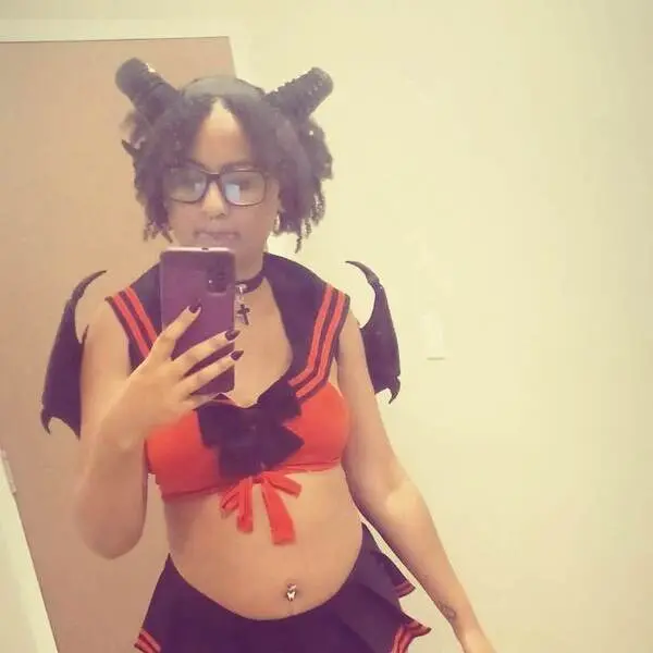 GoddessHoneyXO — GoddessHoneyXO wears a red and black devil costume with horns and wings while taking a mirror selfie.