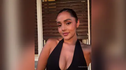 FabianaLima poses in a black halter-neck top with her hair pulled back in a sleek bun.
