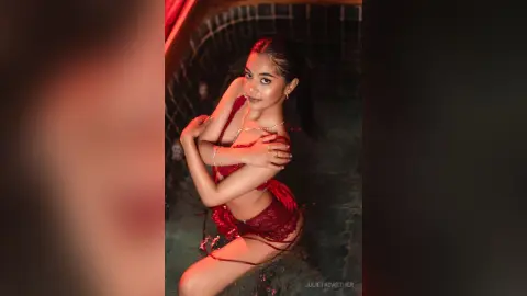 Young woman in a red lace bikini relaxing in a dimly lit pool with a moody, romantic atmosphere.