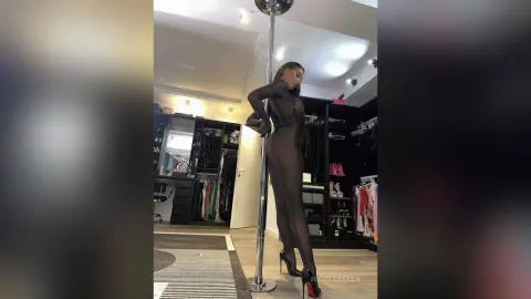 NicoleBella stands naked against a silver pole wearing a sheer black bodysuit in a walk-in closet.