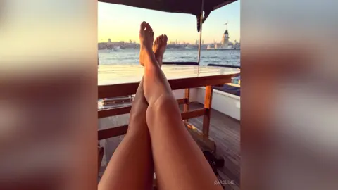 Relaxed person relaxing on a wooden deck overlooking a city skyline at sunset.