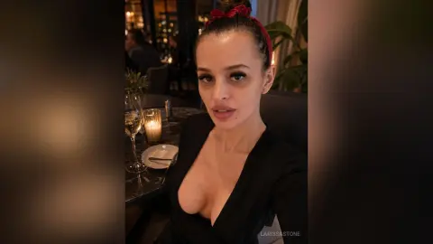 Glamorous woman in a black low-cut dress enjoying a romantic candlelit dinner at a moody upscale restaurant.