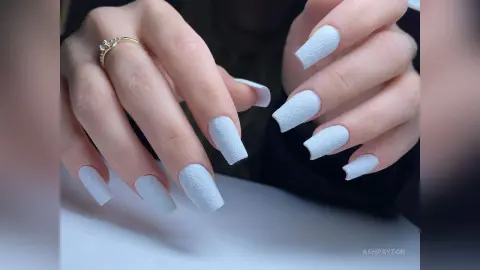 Close-up of elegant light blue matte manicure on female hands with a gold ring.