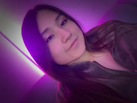 MiaHarveyyy looks into the camera wearing a dark zip-up jacket under purple neon lighting.