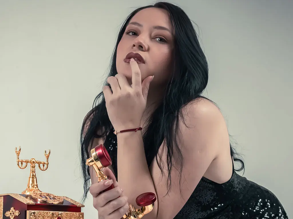 Elegant woman in a black sequin dress posing thoughtfully with a vintage gold trophy in a studio setting.