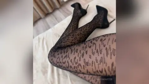 Woman wearing leopard print tights and black high heels lounging on a white bed for a stylish look.
