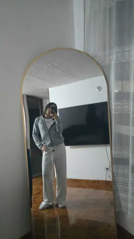 Woman in grey zip-up hoodie and white sweatpants posing in a mirror for a cozy loungewear outfit look.