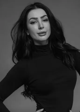 Anelinsa posing in a black turtleneck with her long dark hair flowing over her shoulders.
