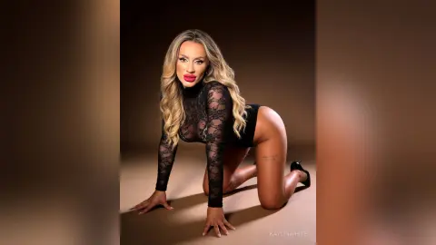 Glamorous blonde woman in a black lace bodysuit posing confidently against a dark studio background.