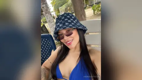 Smiling woman in a blue bikini and denim bucket hat relaxing outdoors on a sunny summer day.