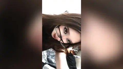 JosefinaHancin wearing black glasses and looking up with her long brown hair framing her face.