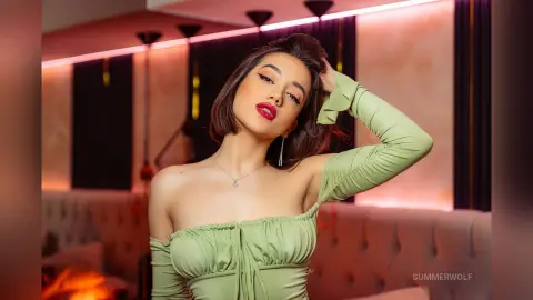 Summer poses in a light green off-the-shoulder top with her hand in her short brown hair.