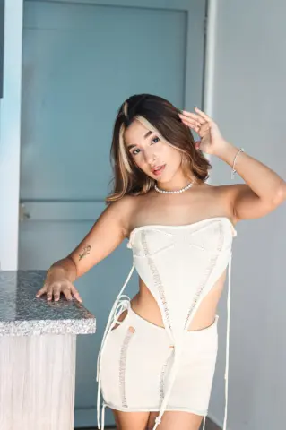 Young woman in a white strapless knit co-ord set posing in a bright modern room.