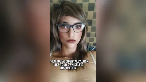 Young woman with glasses and brown hair looking thoughtfully at the camera in a casual indoor setting.