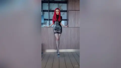 Elegant woman with red hair in a black mini dress posing on a modern balcony at dusk.