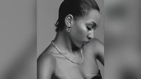 Elegant woman in silver statement jewelry and layered necklaces posing in a moody black and white portrait.