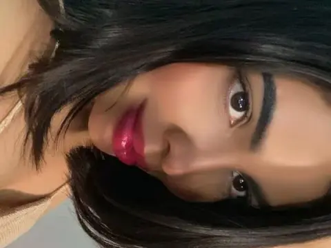 Close-up portrait of a young woman with dark hair and pink lipstick posing with a soft, natural expression.