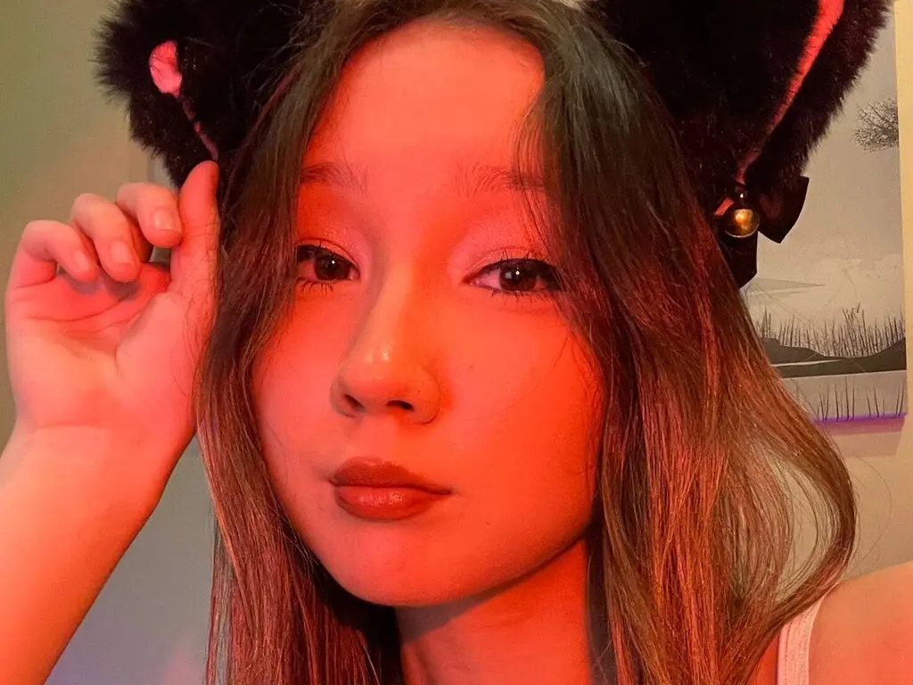 NolanAshgrave wearing black cat ears and looking at the camera with long brown hair and red lighting.
