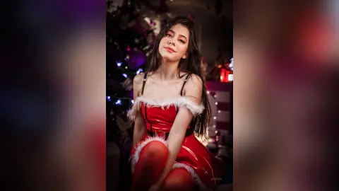 JessieLiu poses in a red satin holiday outfit with white trim, looking at the camera with long dark hair.