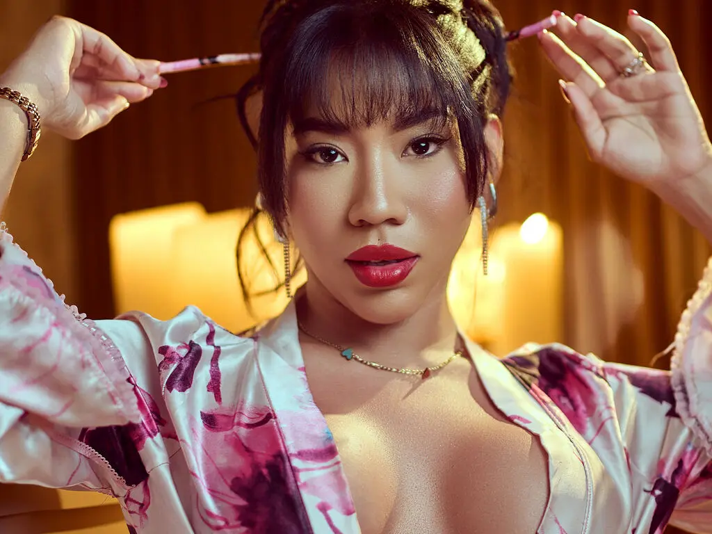 Glamorous woman in a floral silk robe with red lipstick posing in warm candlelight.
