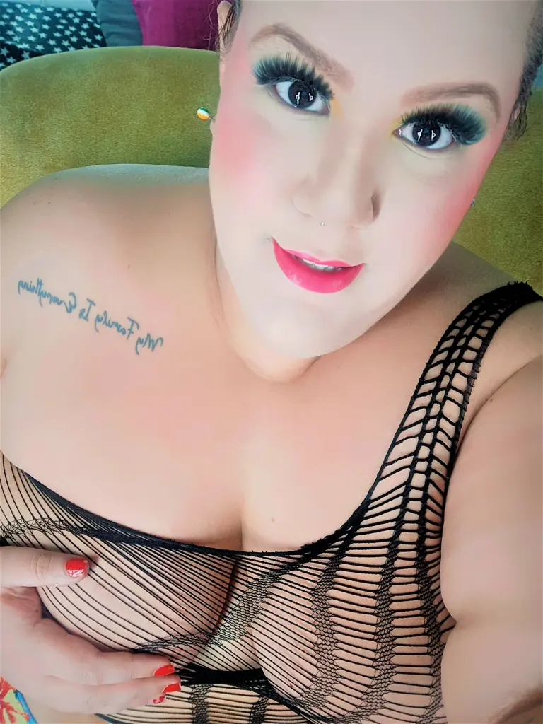 giamorryz poses in a black top, showing her cleavage and long brown hair in a close-up selfie.