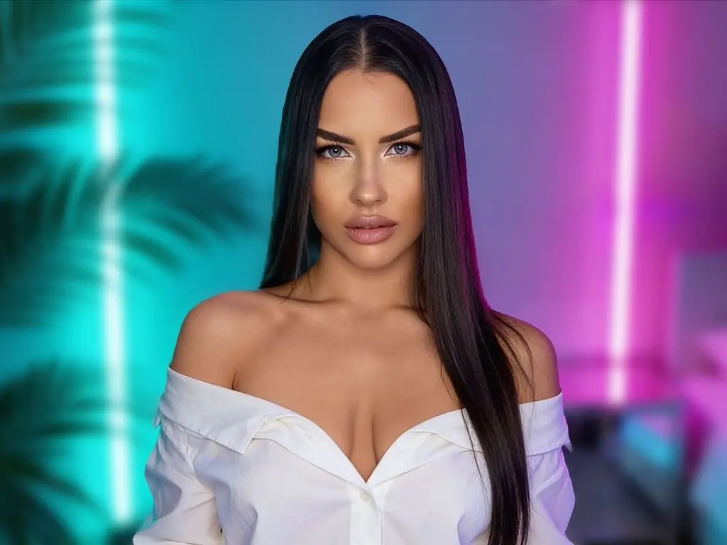 Beautiful woman in a white off-the-shoulder blouse posing against a vibrant teal and pink neon light background.