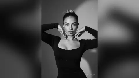 Elegant woman in a black long-sleeve bodysuit posing against a minimalist studio background in black and white.