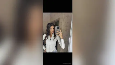 CatherineThomase — CatherineThomase takes a mirror selfie wearing a white long-sleeve top and light blue denim shorts.