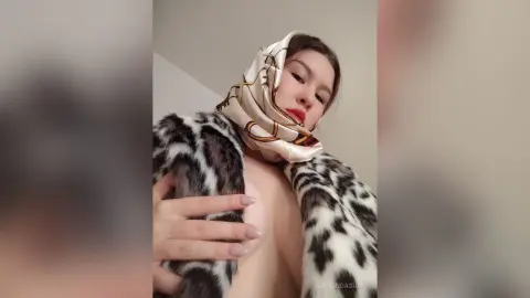 Glamorous woman in a patterned silk headscarf and faux fur coat posing with a luxurious mood.