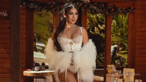 Glamorous woman in a white lace corset and fluffy faux fur stole posing in a tropical garden setting.