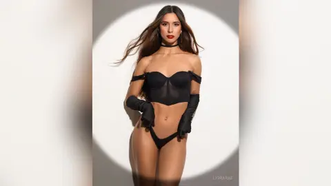 Elegant woman in a black corset and long gloves posing against a studio spotlight background.