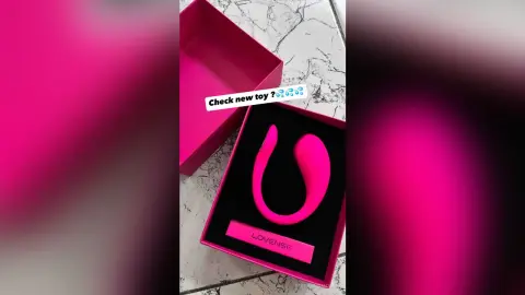 Pink Lovense wellness device in an open gift box on a marble floor surface.