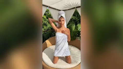 Young woman in a white towel and hair wrap relaxing in a tropical resort cabana.