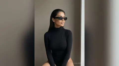 Stylish woman in a black long-sleeve turtleneck bodysuit and sunglasses posing in a minimalist modern setting.