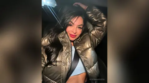 Young woman in a metallic bronze puffer jacket posing inside a car at night.