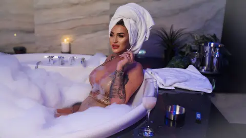 Relaxed woman in a gold bikini relaxing in a bubbly bathtub at a luxury spa setting.