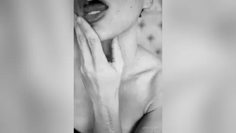 Close-up black and white portrait of a woman touching her face in a moody, artistic aesthetic.