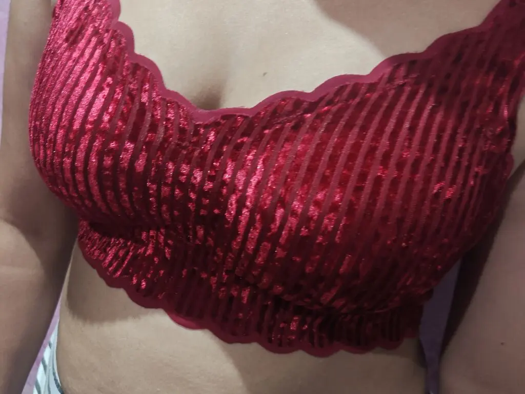Close-up of a woman wearing a luxurious red ribbed velvet bralette in a soft indoor setting.