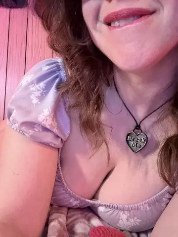 MartaShadow smiles wearing a light purple floral puff-sleeve top and a heart-shaped 'Break Me' necklace.