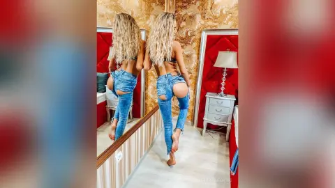 ChristineDavis poses with her back to the camera, wearing ripped blue jeans that expose her bare butt and lower back, showing off her long blonde hair.