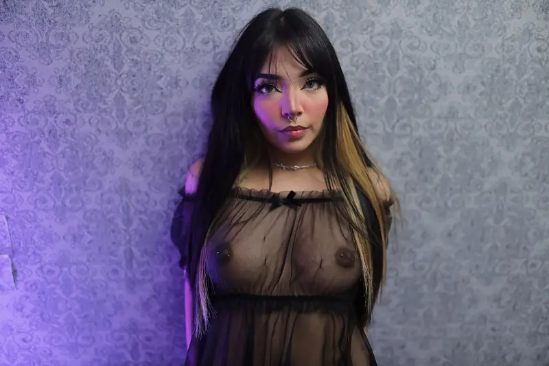 Barbara_Hill poses with her hands near her face, wearing a black tank top and a black choker, showing her dark hair and red lipstick.