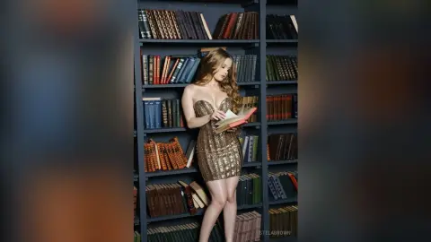 Elegant woman in a shimmering gold sequin dress reading a book in a moody vintage library setting.