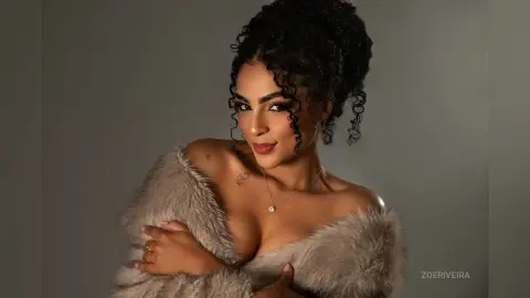 Glamorous woman in a plush faux fur coat posing with elegant makeup against a neutral studio background.